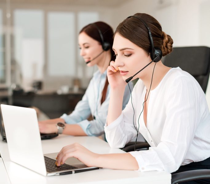 female-operator-call-center-answers-clients-with-headset-laptop-tech-support-office