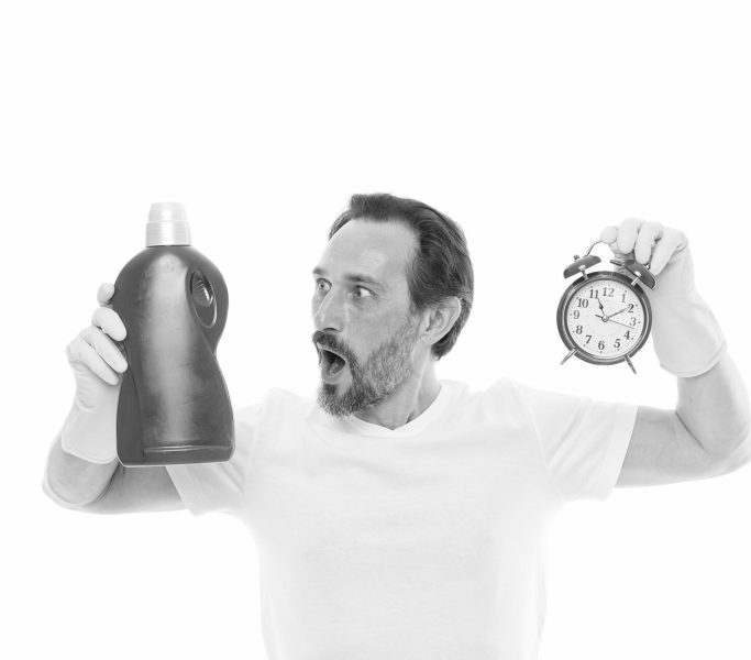 Instant effect. Easy and quickly. Save your time with this cleaning product. Man in rubber gloves hold bottle liquid soap cleaning agent and clock. Bearded guy cleaning home. Cleanup concept. Faster.